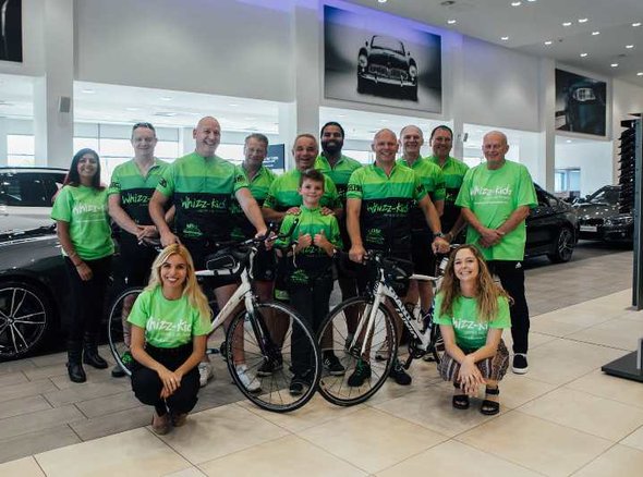 A group of staff at Jardine Motor Group inside a car showroom